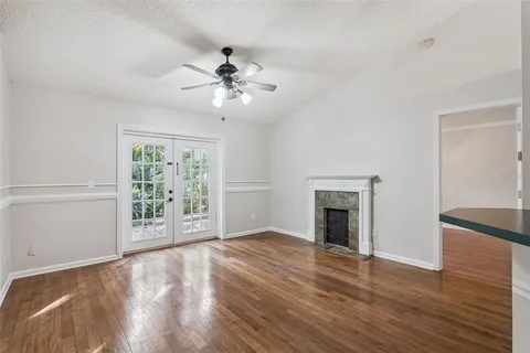 an empty room with wooden floor fan and windows