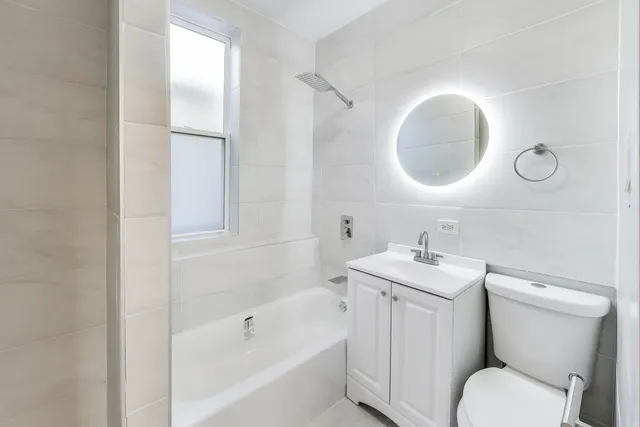 a bathroom with a toilet sink vanity tub and mirror