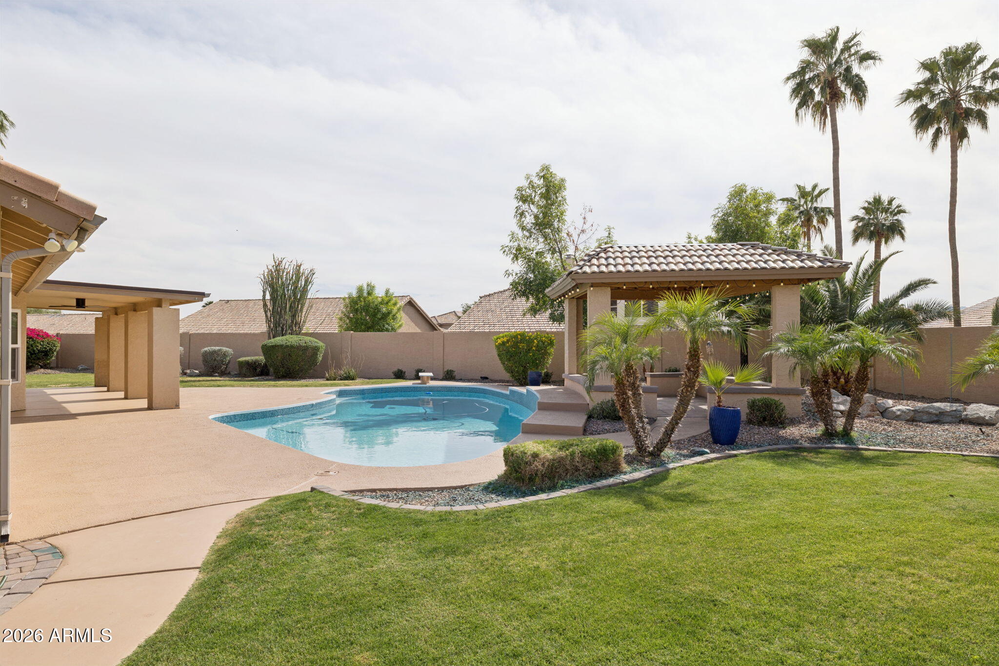 2451 East Dry Creek Road Phoenix, AZ 85048 - Photo 40 of 56 a view of a backyard with table and chairs potted plants and palm tree