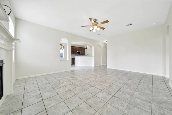 a view of an empty room and chandelier fan