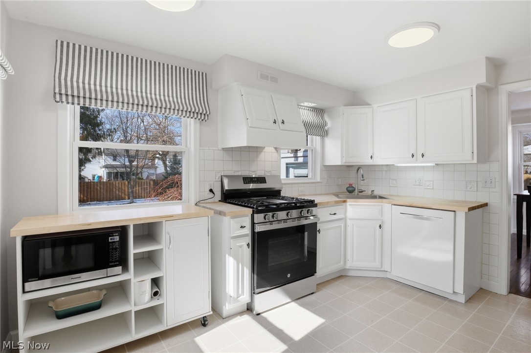 1390 Brainard Road Lyndhurst, OH 44124 - Photo 13 of 33 Kitchen featuring stainless steel appliances, white cabinetry, wooden counters, backsplash, and light tile patterned flooring
