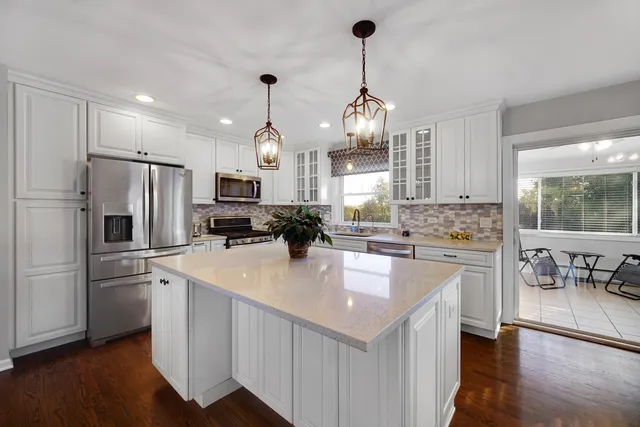 a kitchen with kitchen island granite countertop appliances a sink a center island and cabinets
