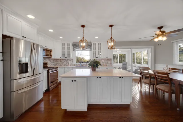 a kitchen with stainless steel appliances kitchen island granite countertop a kitchen island hardwood floor and a sink