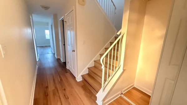 a view of a hallway with wooden floor and staircase