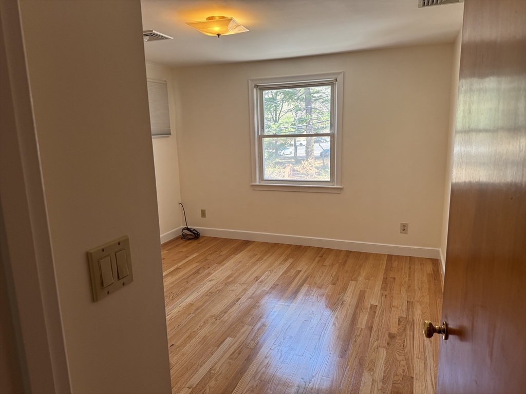 174 Forest Street Waltham, MA 02452 - Photo 5 of 15 an empty room with wooden floor and windows