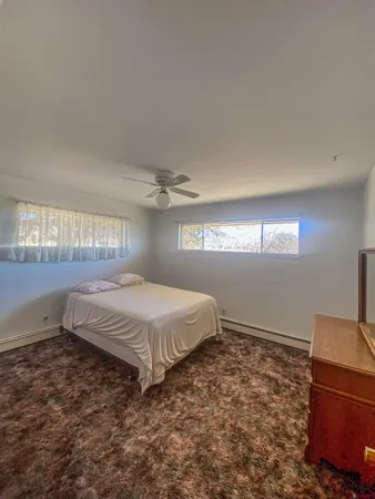 a bed sitting in a spacious bedroom next to a window