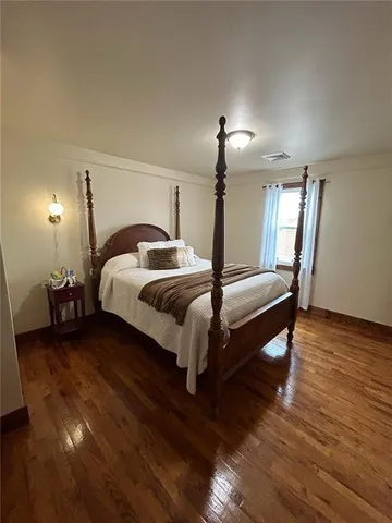 a spacious bedroom with a bed and wooden floor
