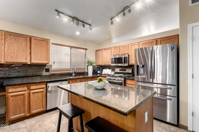 a kitchen with stainless steel appliances granite countertop a refrigerator a stove a sink a dining table and chairs