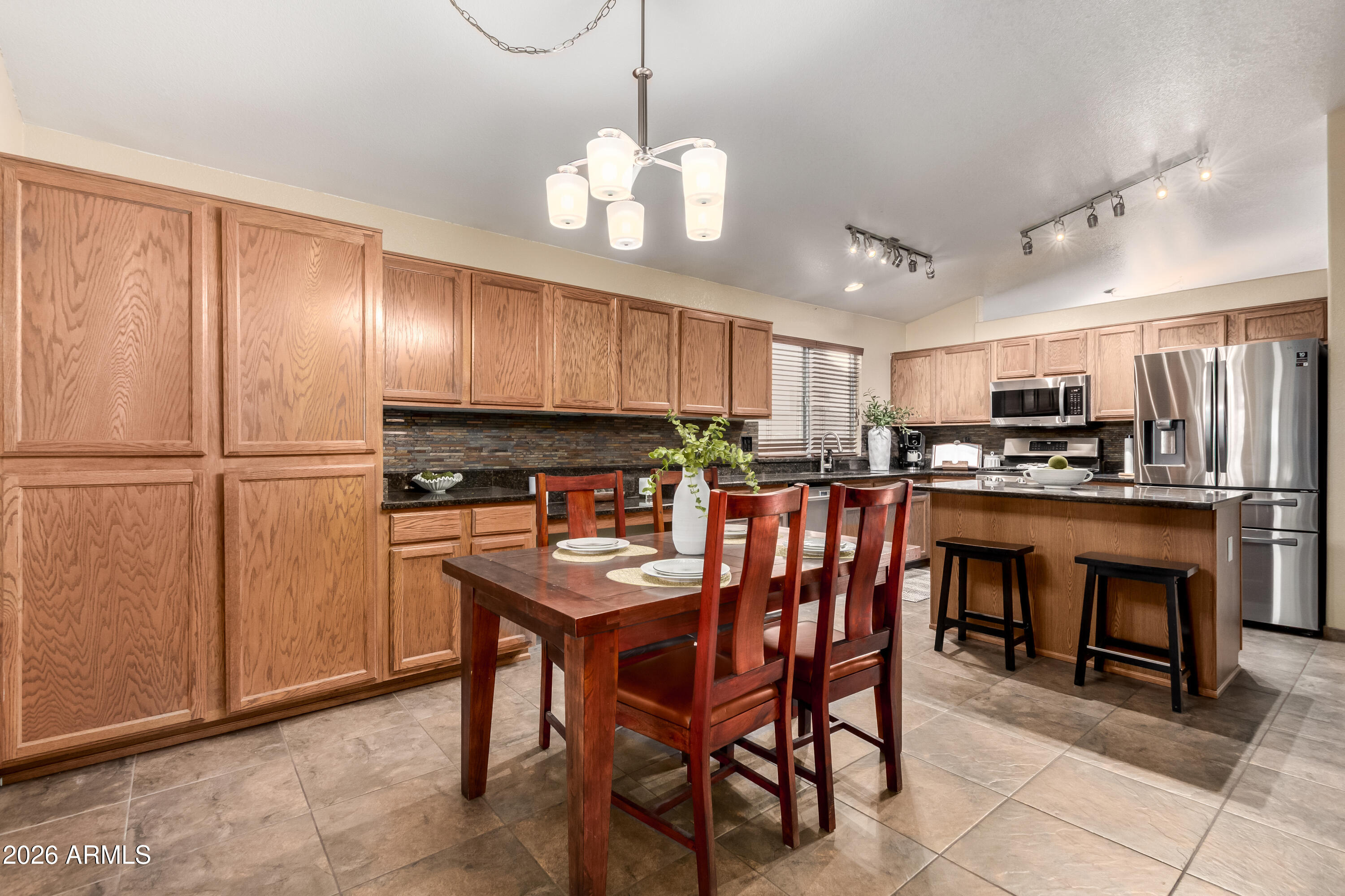 1147 North Marvin Street Gilbert, AZ 85233 - Photo 7 of 31 a kitchen with stainless steel appliances granite countertop a refrigerator a sink dishwasher a dining table and chairs with wooden floor