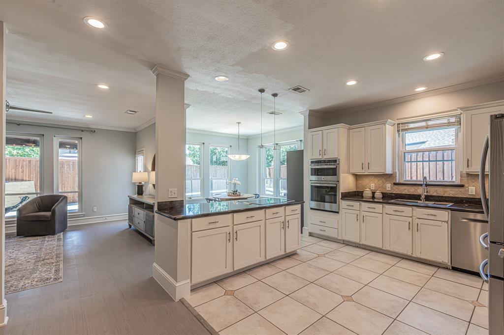 300 Sundance Circle Irving, TX 75063 - Photo 20 of 39 Open-concept kitchen featuring an island with a dark countertop, light-colored cabinetry, stainless steel appliances, and recessed lighting