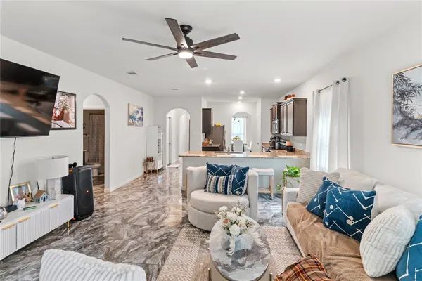 a living room with furniture kitchen view and a large window