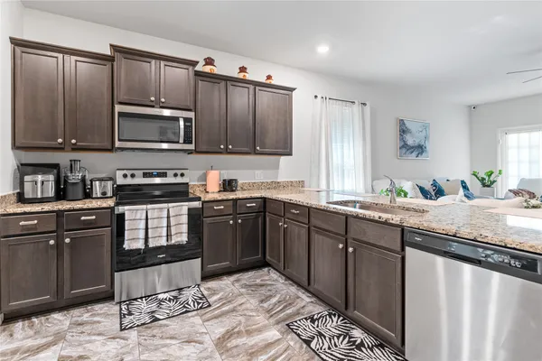 a kitchen with stainless steel appliances granite countertop a stove sink microwave and cabinets