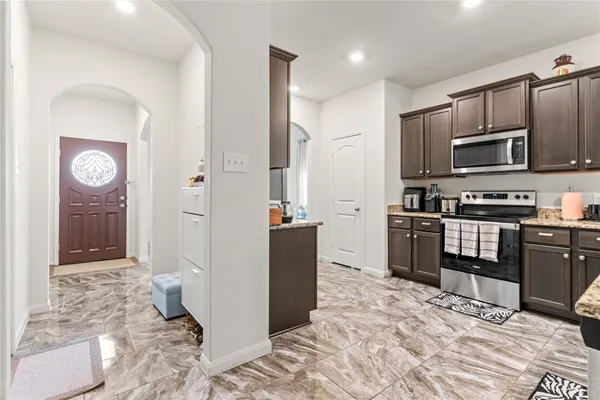 a kitchen with stainless steel appliances kitchen island granite countertop a refrigerator and a stove top oven