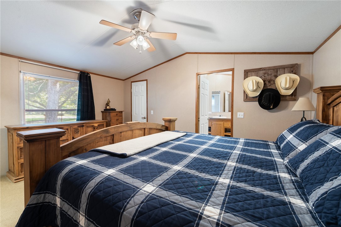 1061 Tafelski Road New Waverly, TX 77358 - Photo 16 of 37 a bedroom with a large bed and a chandelier