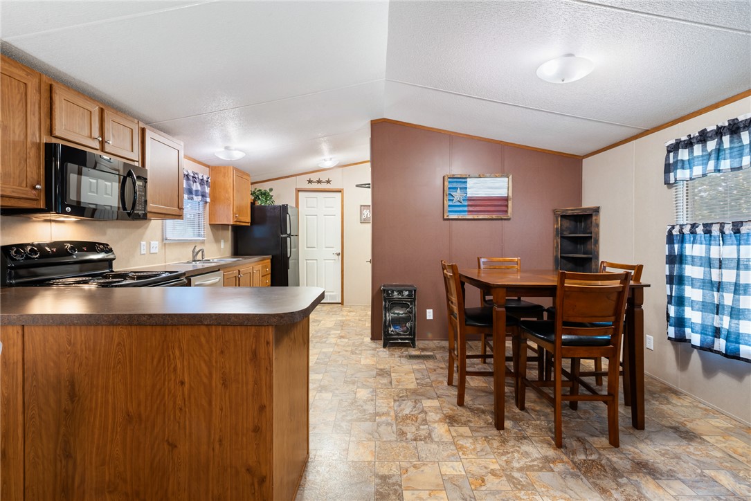 1061 Tafelski Road New Waverly, TX 77358 - Photo 10 of 37 a kitchen with stainless steel appliances granite countertop a stove a refrigerator a dining table and chairs with wooden floor