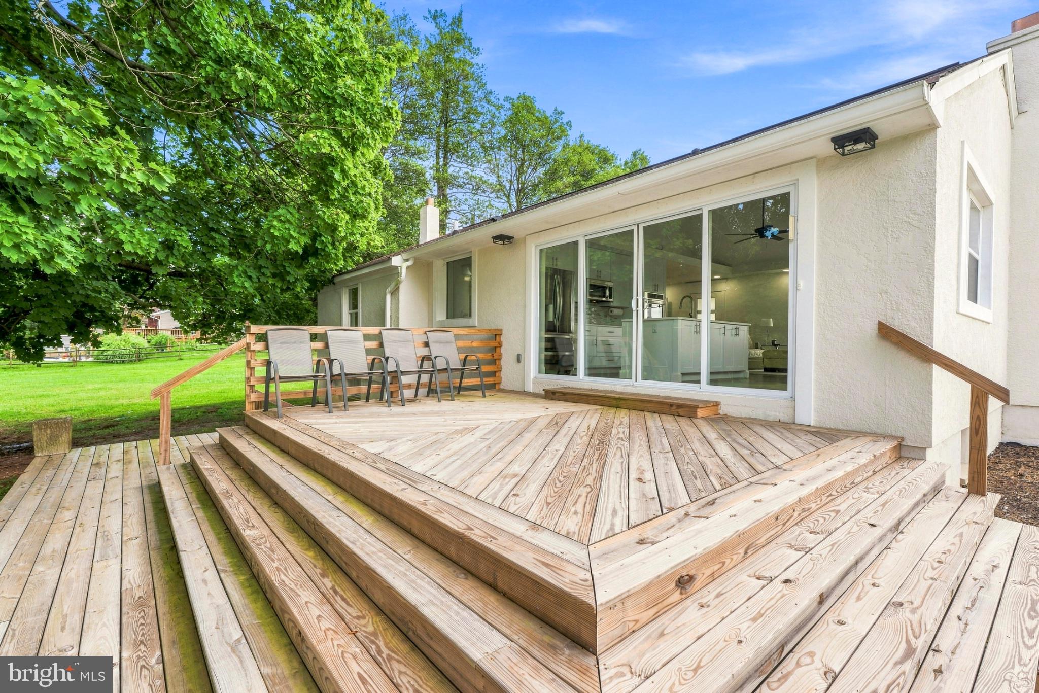 Sunny deck with lush green backdrop.