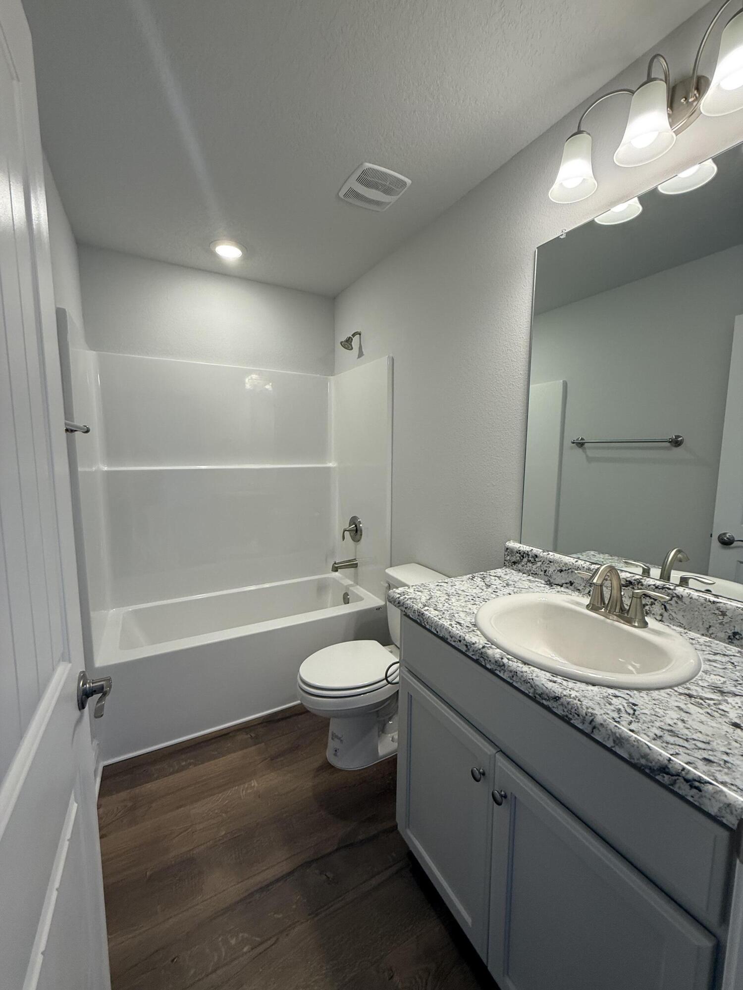 6011 Crocket Cove Crestview, FL 32539 - Photo 7 of 18 a bathroom with a granite countertop sink toilet mirror and bathtub