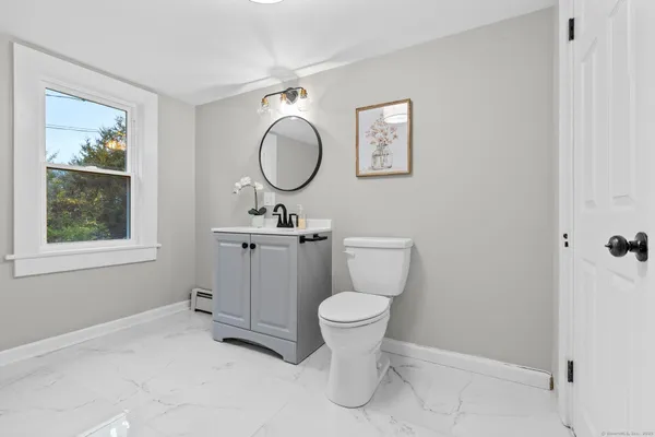 a bathroom with a toilet sink a mirror and window