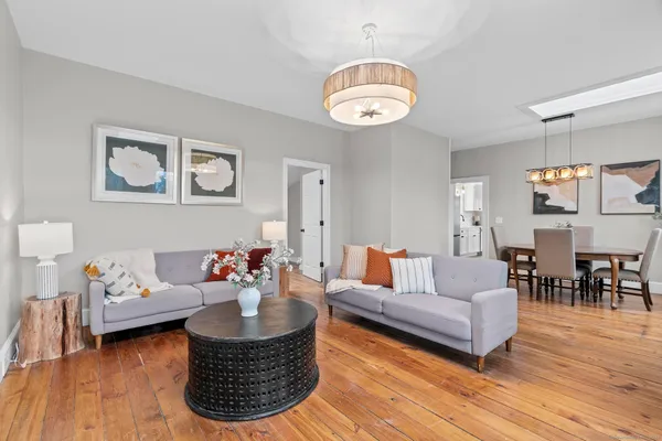a living room with furniture potted plant and kitchen view