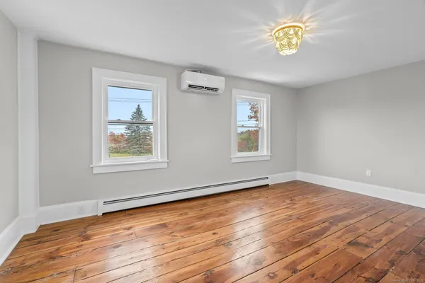 a view of an empty room with a window and wooden floor