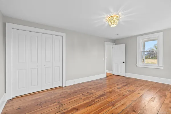 a view of an empty room with window and wooden floor
