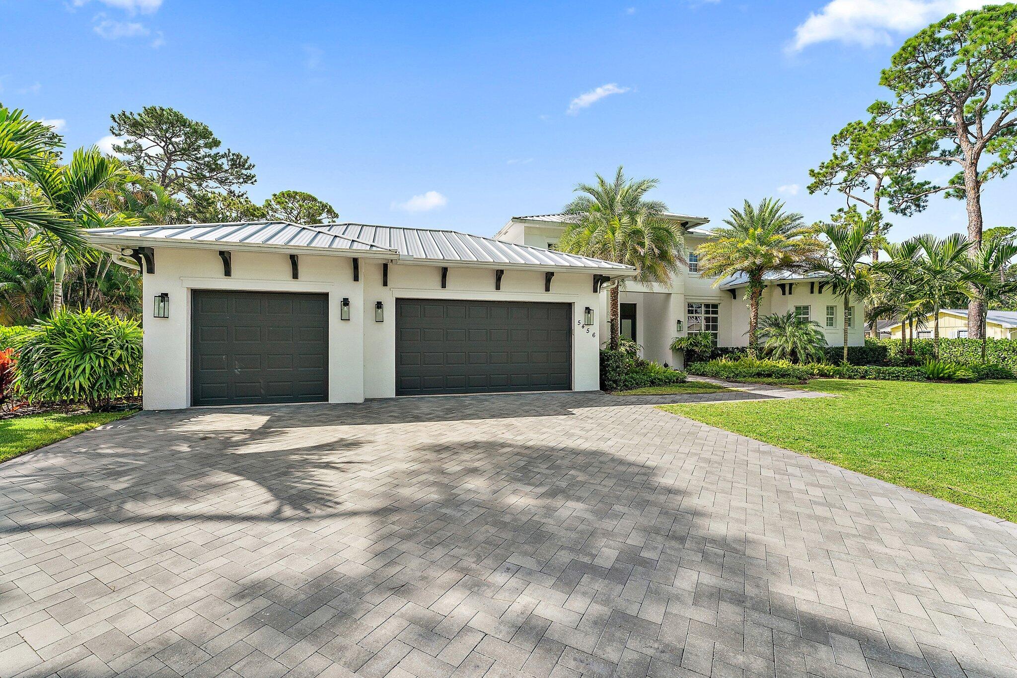 5456 Hibiscus Road Jupiter, FL 33458 - Photo 28 of 48 a front view of a house with a yard and garage