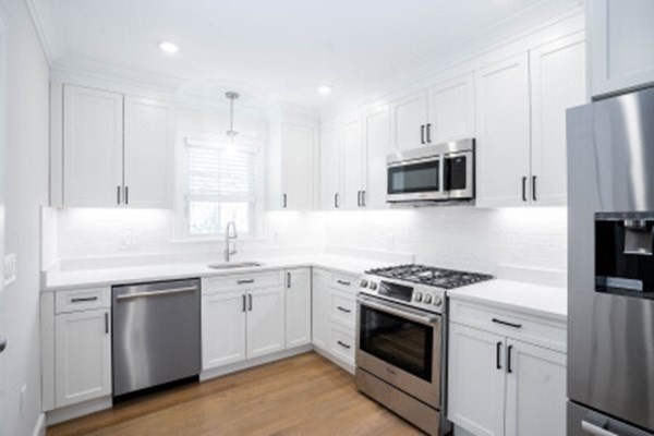 14 Atkins Street, Unit 1 Boston, MA 02135 - Photo 2 of 11 a kitchen with white cabinets and stainless steel appliances