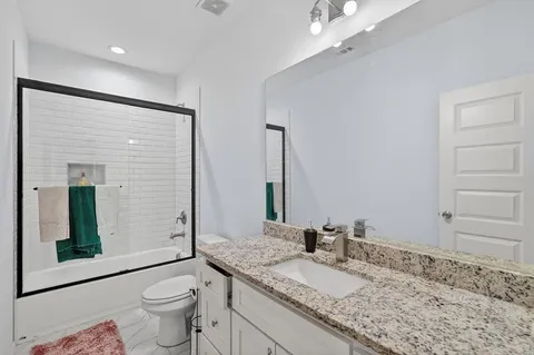 a bathroom with a granite countertop sink a toilet and mirror