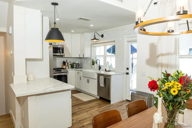 a kitchen that has a lot of white cabinets and stainless steel appliances