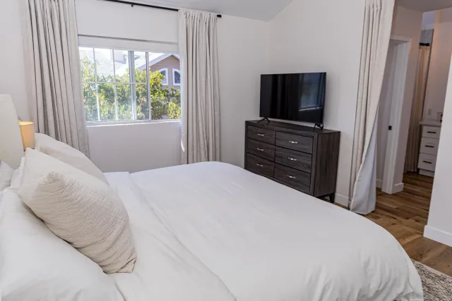 a bedroom with a bed and a flat tv screen on dresser