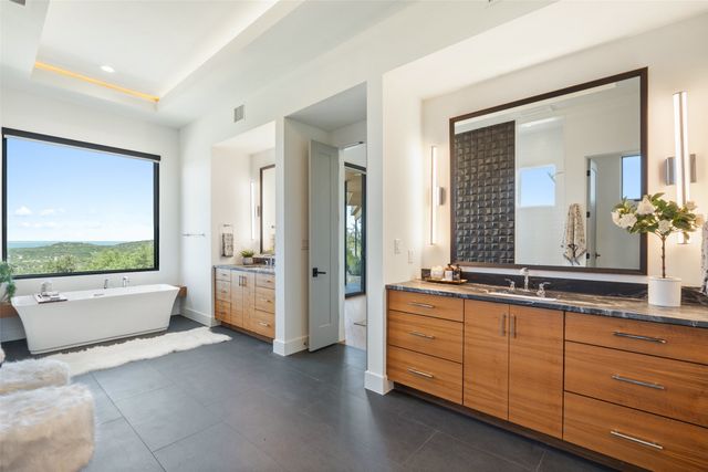 a spacious bathroom with a tub a double vanity sink a mirror and a shower
