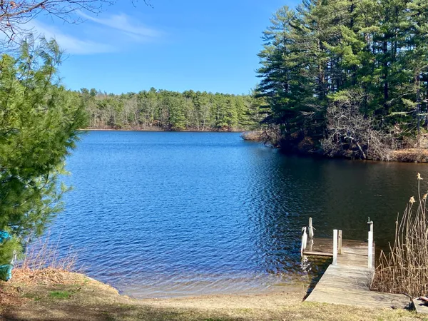 a view of a lake with a floor to ceiling window and wooden fence