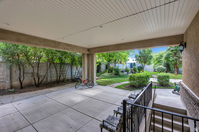 650 East Center Street Alpine, UT 84004 - Photo 31 of 38 Covered patio with square-paneled concrete flooring, accented by a concrete fence and mature trees