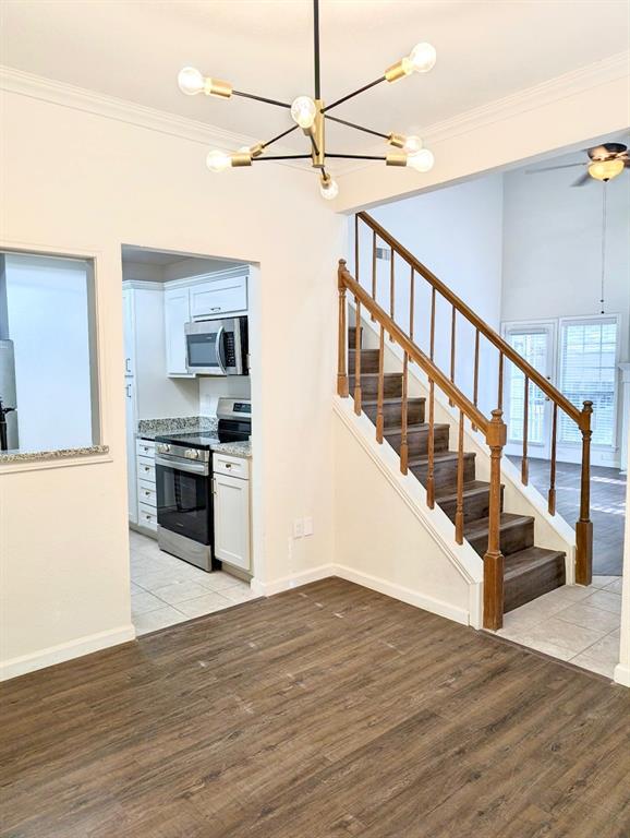 12680 Hillcrest Road, Unit 4101 Dallas, TX 75230 - Photo 26 of 37 Open-concept interior featuring wood-finish flooring, a modern sputnik chandelier, and a staircase with wood newel posts and handrails