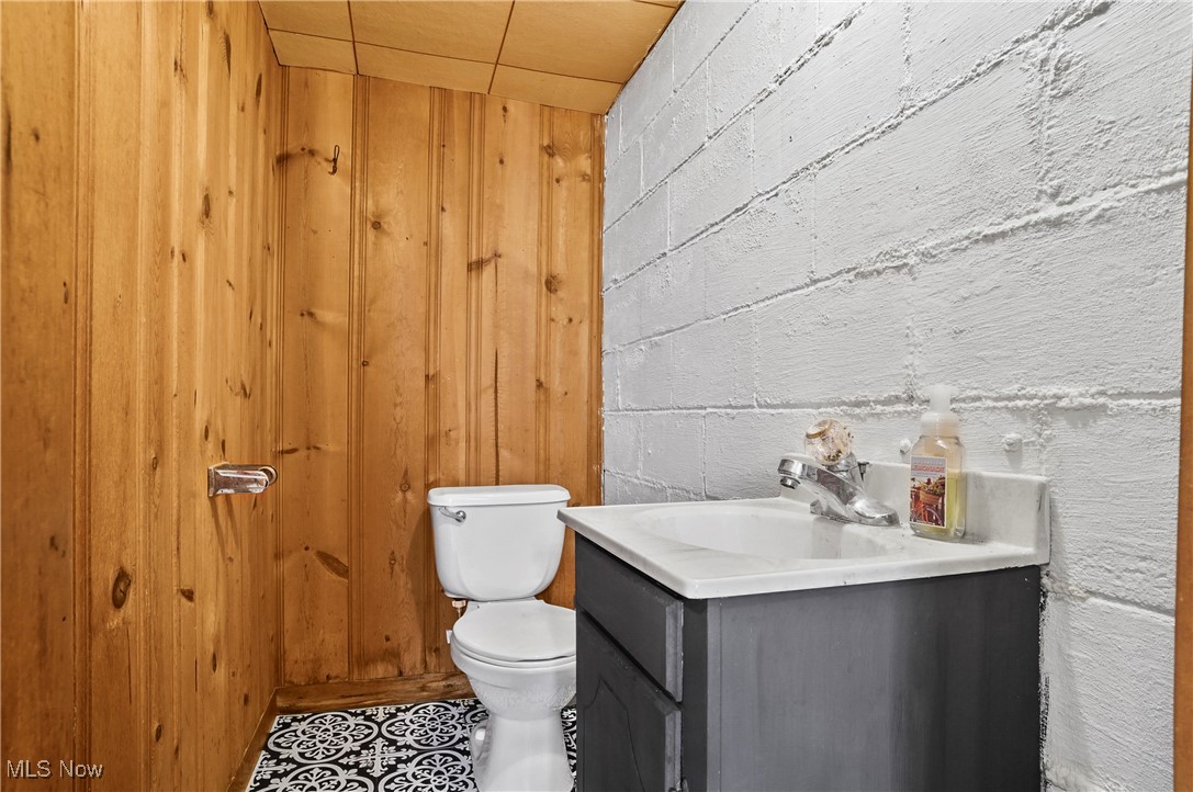 1071 Chalker Street Akron, OH 44310 - Photo 22 of 23 Bathroom with tile patterned flooring, wood walls, vanity, and toilet