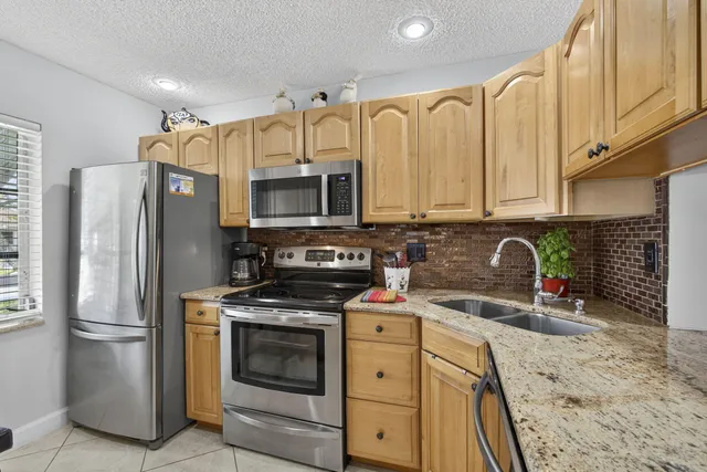 a kitchen with stainless steel appliances a stove a sink a microwave a refrigerator and cabinets