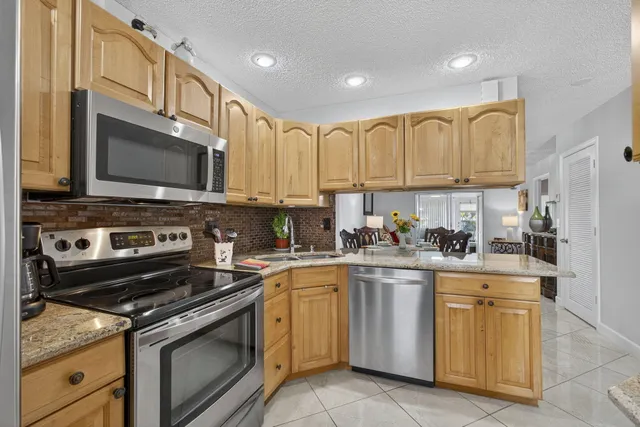 a kitchen with stainless steel appliances granite countertop a sink and a refrigerator