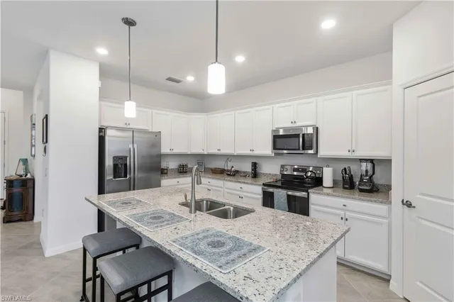 a kitchen with microwave a refrigerator a stove a sink and chairs