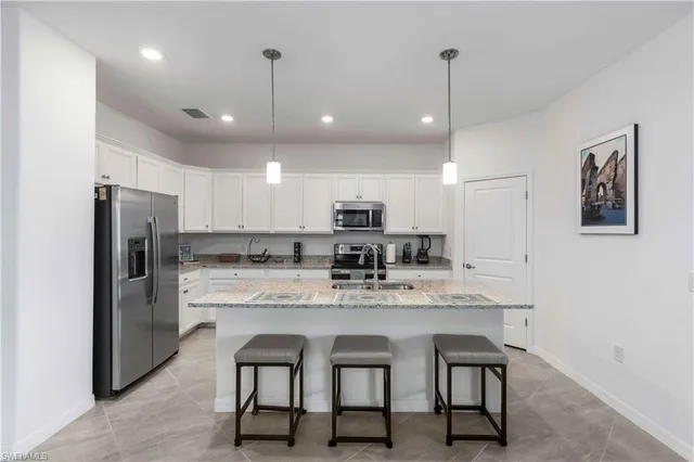a kitchen with refrigerator a sink and chairs