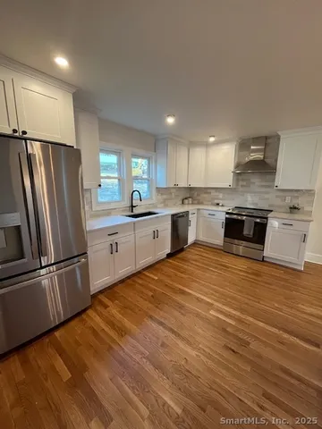 a large kitchen with stainless steel appliances granite countertop a refrigerator and a stove top oven