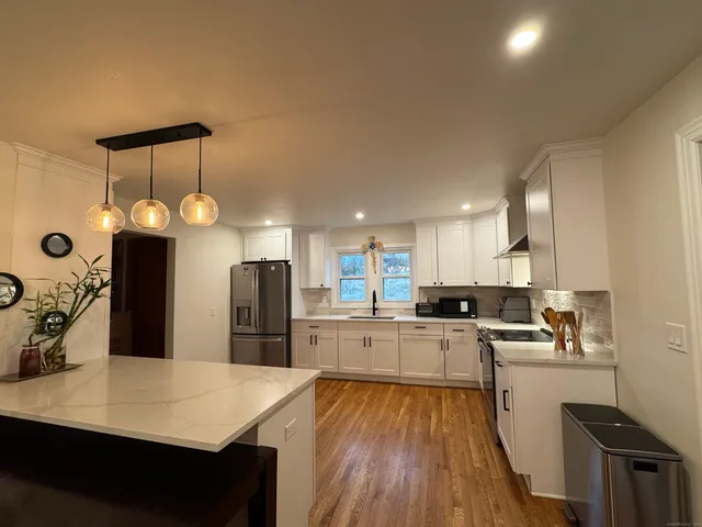 a kitchen with refrigerator a stove a sink dishwasher and a dining table with wooden floor