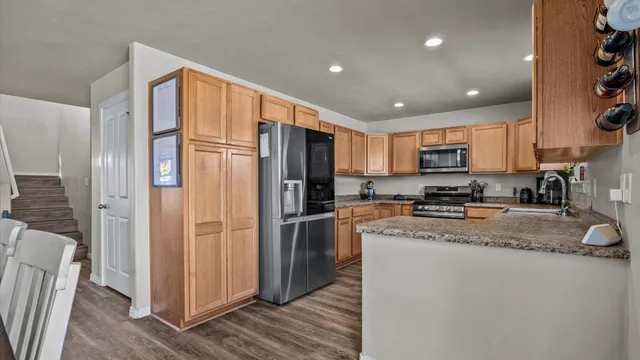 a kitchen with stainless steel appliances granite countertop a refrigerator a stove a sink a washer and dryer