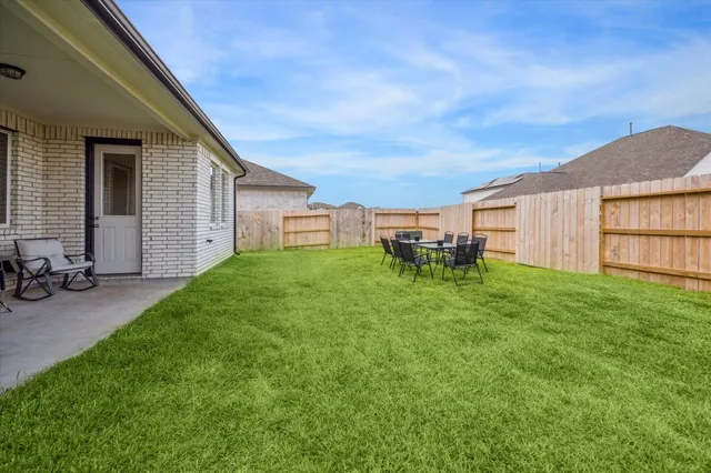 a view of a backyard with table and chairs and a barbeque