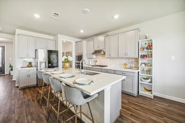 a kitchen with a sink a stove a refrigerator and white cabinets