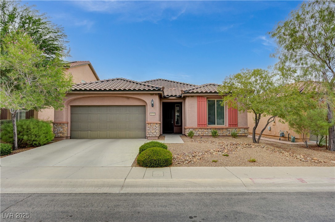 6970 Motley Road Las Vegas, NV 89178 - Photo 1 of 52 Mediterranean/Spanish-style home with stone and stucco siding, two-car garage, tiled roof, and low-maintenance desert lanscaping