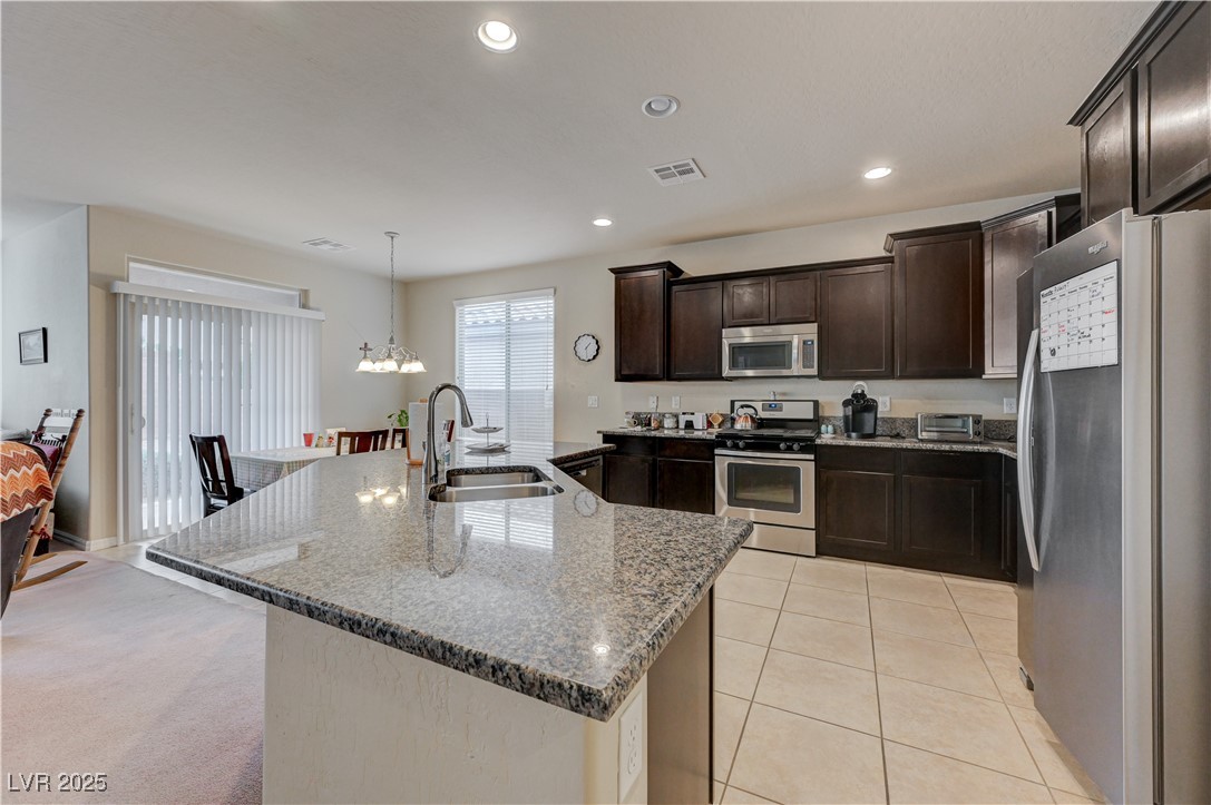 6970 Motley Road Las Vegas, NV 89178 - Photo 13 of 52 Kitchen with island, espresso cabinets, stainless steel appliances, recessed lighting, granite countertops, pantry, ceramic tile flooring