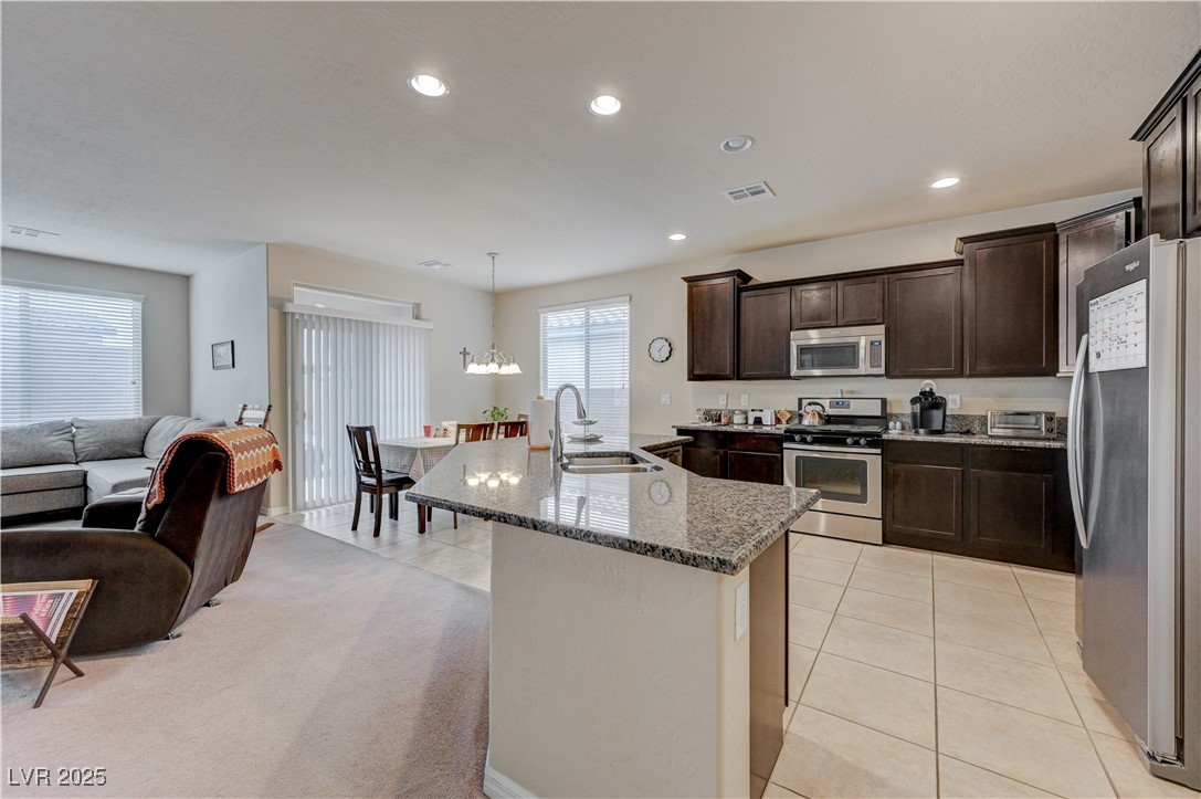 6970 Motley Road Las Vegas, NV 89178 - Photo 14 of 52 Kitchen with island, espresso cabinets, stainless steel appliances, recessed lighting, granite countertops, pantry, ceramic tile flooring