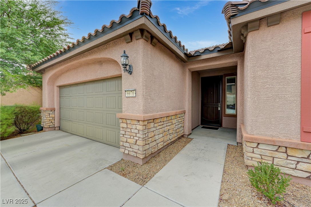 6970 Motley Road Las Vegas, NV 89178 - Photo 3 of 52 Property entrance featuring stone and stucco siding with tile roof and low-maintenance desert lanscaping, plus
two-car garage