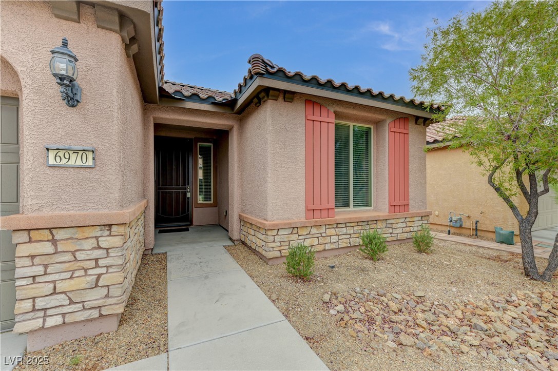 6970 Motley Road Las Vegas, NV 89178 - Photo 4 of 52 Property entrance featuring stone and stucco siding with tile roof and low-maintenance desert lanscaping
