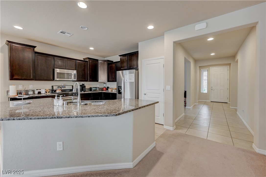 6970 Motley Road Las Vegas, NV 89178 - Photo 6 of 52 Kitchen with island, espresso cabinets, stainless steel appliances, recessed lighting, granite countertops, pantry, ceramic tile flooring